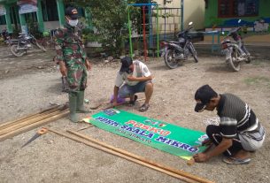 Anggota Satgas TMMD 110 Bojonegoro Membantu Warga Menata Banner