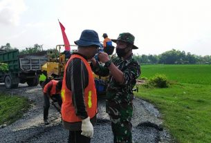 Anggota Satgas TMMD 110 Bojonegoro Ini Pasangkan Masker Ke Warga