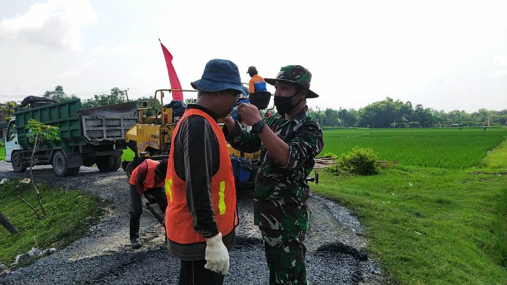 Anggota Satgas TMMD 110 Bojonegoro Ini Pasangkan Masker Ke Warga