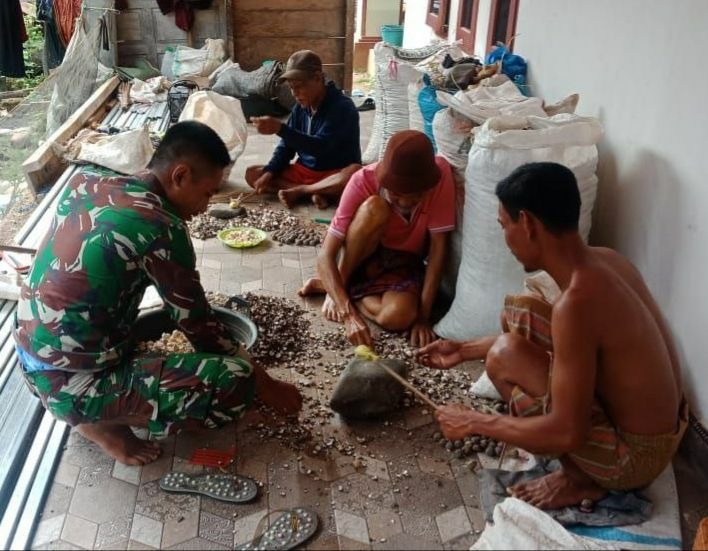 Satgas TMMD Bantu Warga Mengupas Buah Kemiri