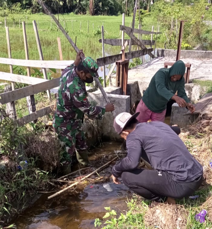 Bersihkan Saluran Pintu Air, Solusi Babinsa Posramil 05/PC Tingkatkan Produksi Sektor Pertanian