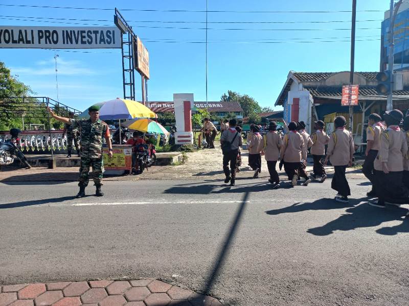 Berikan Rasa Aman, Babinsa Bantu Sebrangkan Anak Sekolah